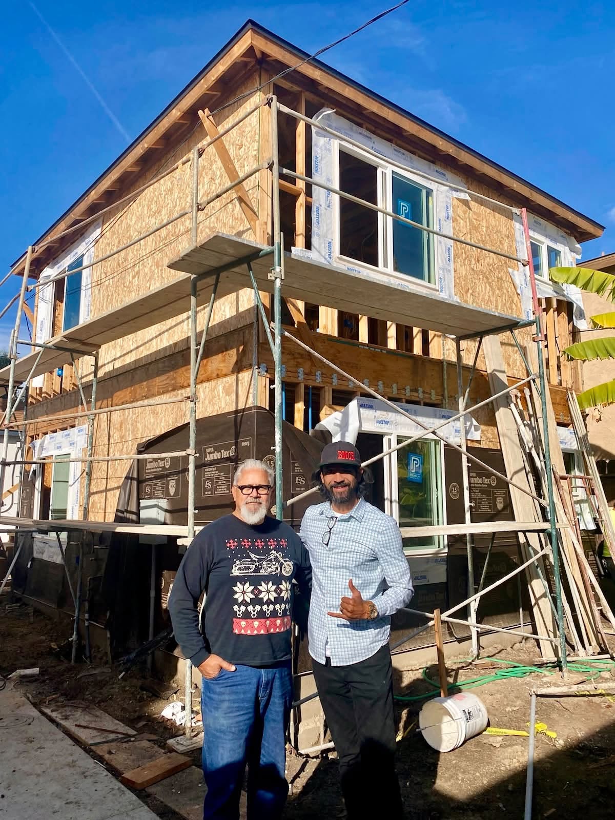 Kalani and his father outside a home under construction